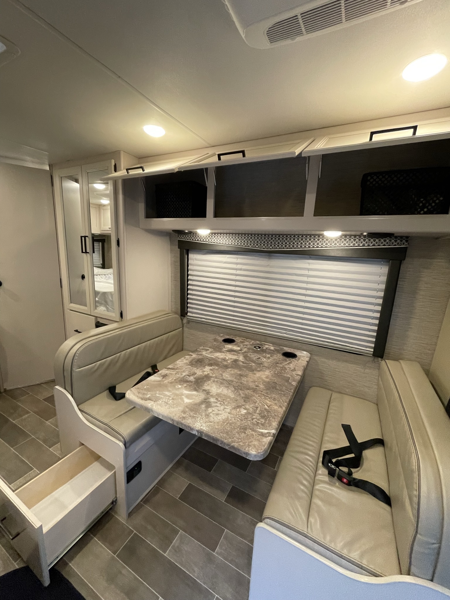 Dinette seating in 2022 Thor Chateau Roadrunner RV with table, storage drawer, and overhead cabinets.